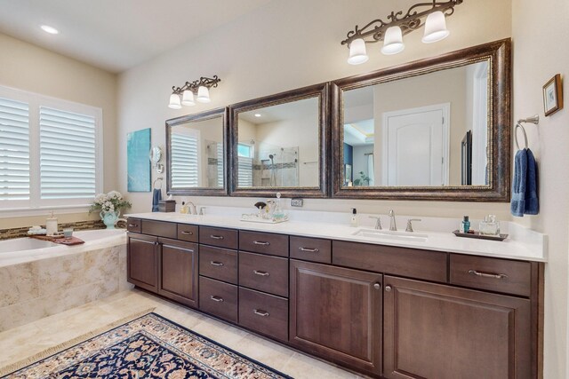 bathroom with tile patterned flooring, vanity, and a relaxing tiled tub