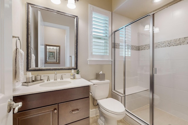 bathroom featuring vanity, toilet, and a shower with shower door