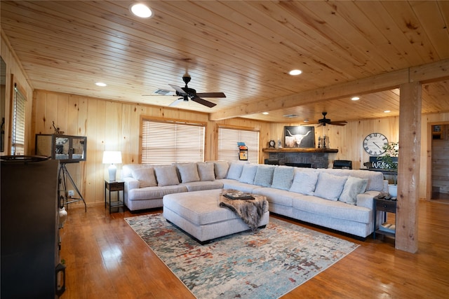 living area with wooden ceiling, recessed lighting, wood finished floors, and a stone fireplace