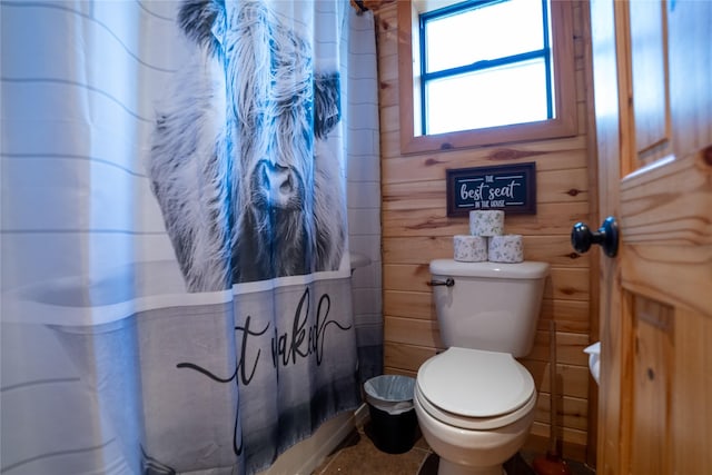 bathroom with wood walls, a shower with shower curtain, and toilet