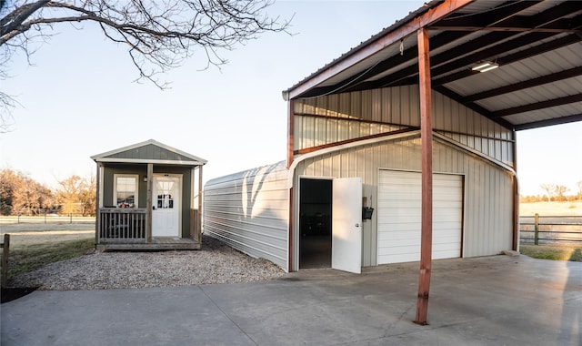 view of outbuilding featuring fence, concrete driveway, and an outdoor structure