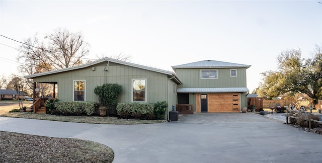 view of front facade featuring concrete driveway and fence