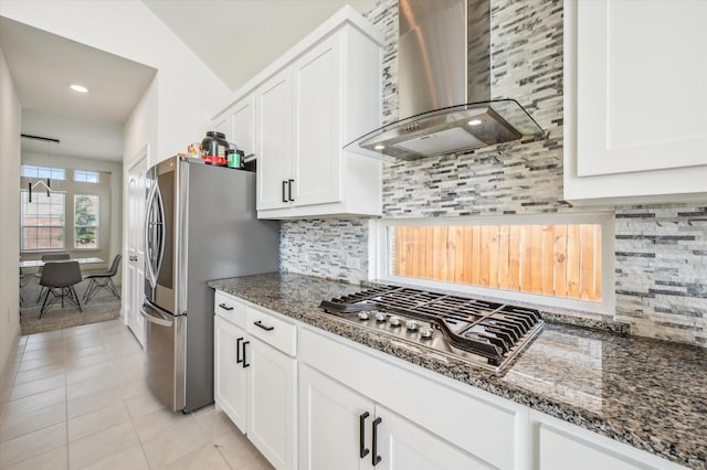 kitchen featuring dark stone counters, white cabinetry, and wall chimney exhaust hood