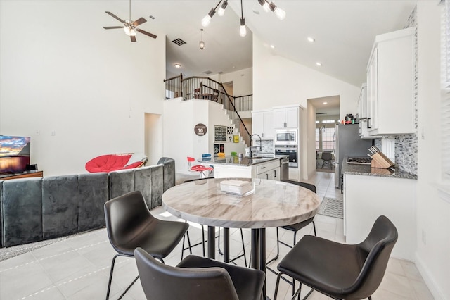 dining space featuring light tile patterned floors, high vaulted ceiling, and sink