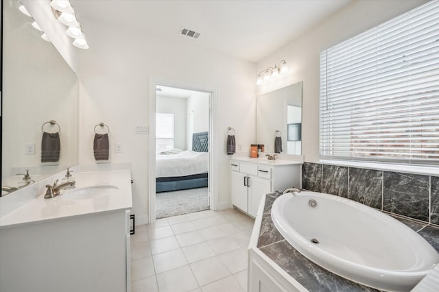 bathroom featuring tile patterned flooring, plenty of natural light, tiled tub, and vanity