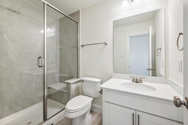 bathroom with wood-type flooring, vanity, toilet, and a shower with shower door