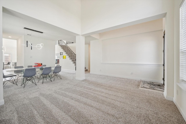 carpeted dining room featuring a towering ceiling