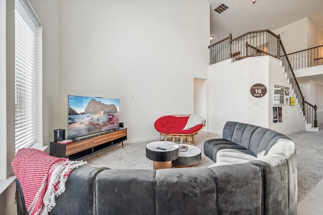 carpeted living room featuring plenty of natural light and a high ceiling