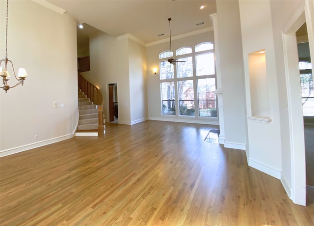 interior space featuring hardwood / wood-style flooring, ornamental molding, a high ceiling, and an inviting chandelier