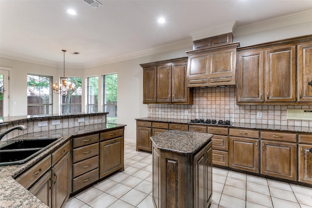 kitchen with sink, hanging light fixtures, a center island, decorative backsplash, and dark stone counters