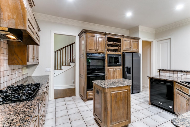 kitchen with crown molding, a center island, black appliances, decorative backsplash, and dark stone counters