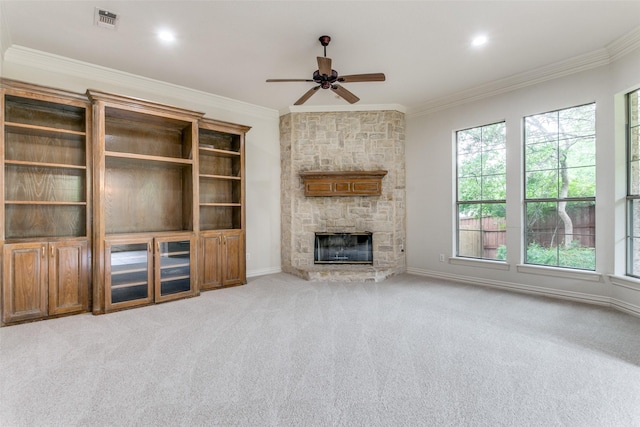 unfurnished living room with ornamental molding, a stone fireplace, and light carpet