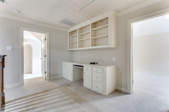 kitchen featuring white cabinetry, light colored carpet, ornamental molding, and built in desk