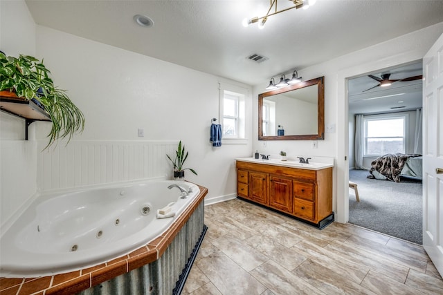 bathroom featuring vanity, a healthy amount of sunlight, and tiled bath