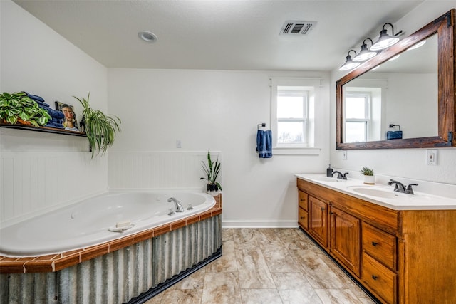 bathroom with vanity and tiled bath