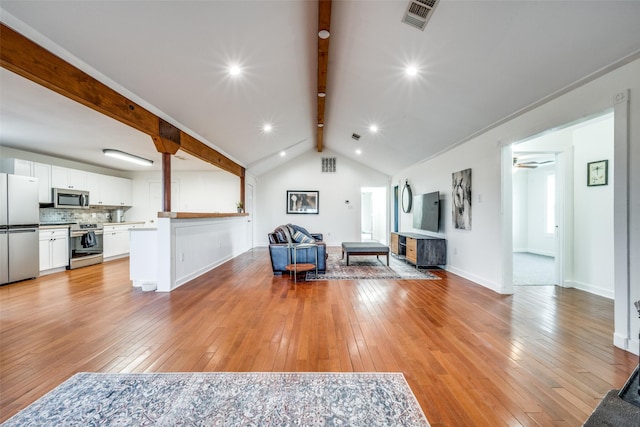 living room with vaulted ceiling with beams, wood-type flooring, and a wood stove