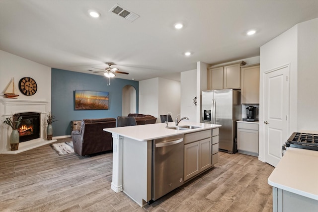 kitchen featuring a center island with sink, gray cabinetry, light wood-type flooring, and appliances with stainless steel finishes