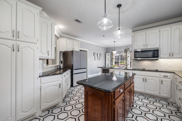 kitchen featuring a center island, ornamental molding, appliances with stainless steel finishes, pendant lighting, and white cabinets