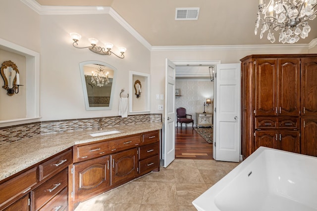 bathroom featuring crown molding, an inviting chandelier, backsplash, vanity, and a tub to relax in