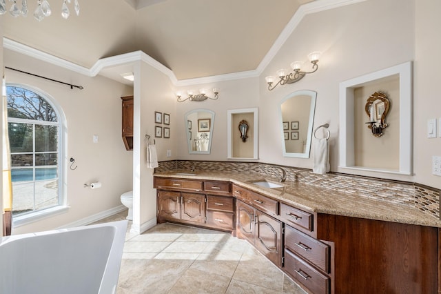 bathroom featuring tile patterned floors, toilet, crown molding, vanity, and a bath