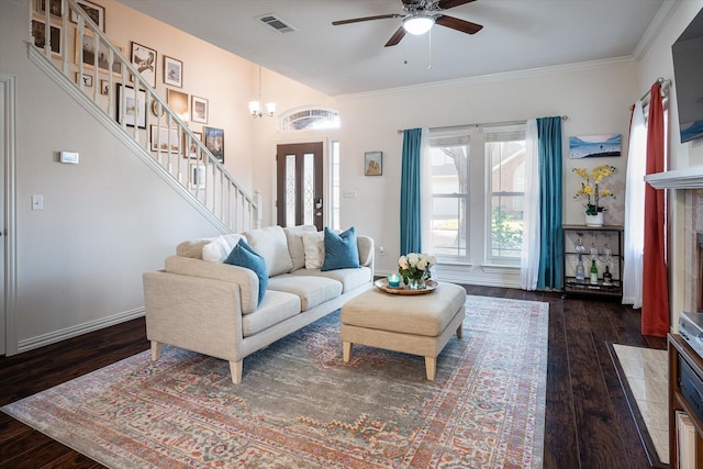 living room featuring ceiling fan with notable chandelier, crown molding, and dark wood-type flooring