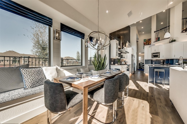 dining space featuring a healthy amount of sunlight, dark hardwood / wood-style flooring, sink, and an inviting chandelier