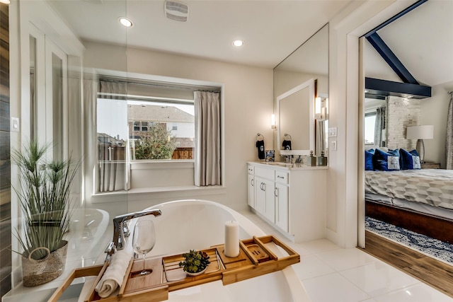 bathroom with tile patterned flooring, a bathtub, vanity, and vaulted ceiling