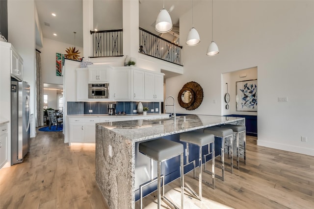 kitchen featuring a towering ceiling, white cabinets, and a spacious island