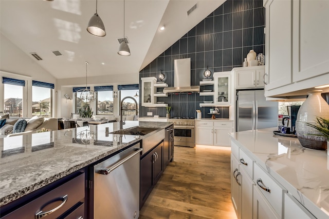 kitchen with sink, stainless steel appliances, range hood, pendant lighting, and white cabinets