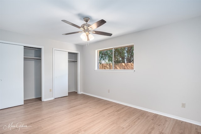 unfurnished bedroom with ceiling fan, light hardwood / wood-style flooring, and two closets