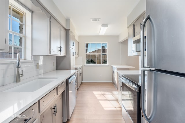 kitchen featuring decorative backsplash, sink, light hardwood / wood-style flooring, and appliances with stainless steel finishes