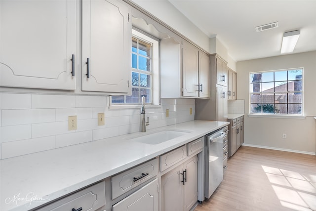 kitchen featuring tasteful backsplash, dishwasher, light hardwood / wood-style floors, and sink