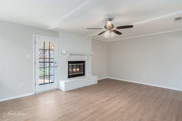 unfurnished living room with beam ceiling, light hardwood / wood-style floors, a brick fireplace, and ceiling fan