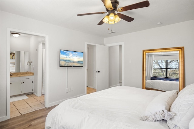 bedroom with ceiling fan, light wood-type flooring, and ensuite bath