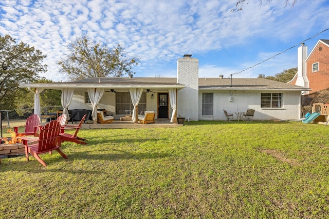 rear view of house featuring ceiling fan and a yard