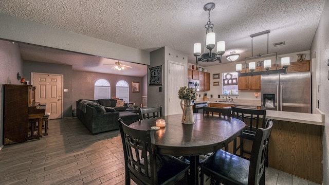 dining room with hardwood / wood-style flooring, sink, ceiling fan with notable chandelier, and a textured ceiling