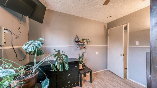 interior space featuring ceiling fan, light hardwood / wood-style floors, and a textured ceiling