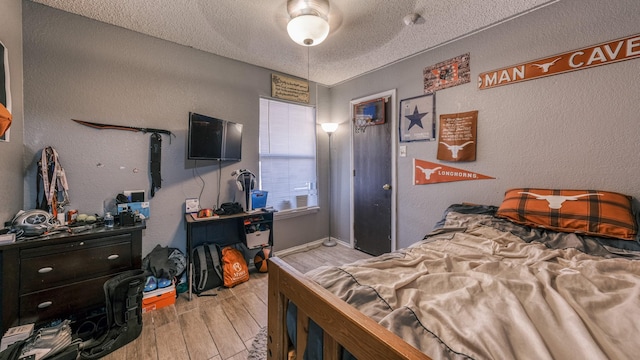 bedroom featuring ceiling fan, light hardwood / wood-style floors, and a textured ceiling