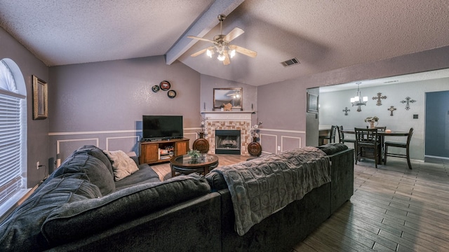 living room featuring ceiling fan with notable chandelier, vaulted ceiling with beams, hardwood / wood-style floors, and a textured ceiling