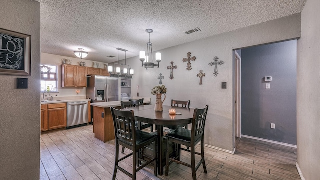 dining area with a chandelier, sink, and a textured ceiling