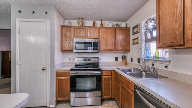 kitchen with appliances with stainless steel finishes, sink, and a textured ceiling