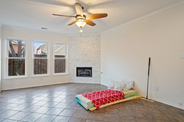 unfurnished room featuring a stone fireplace, ceiling fan, tile patterned flooring, and ornamental molding