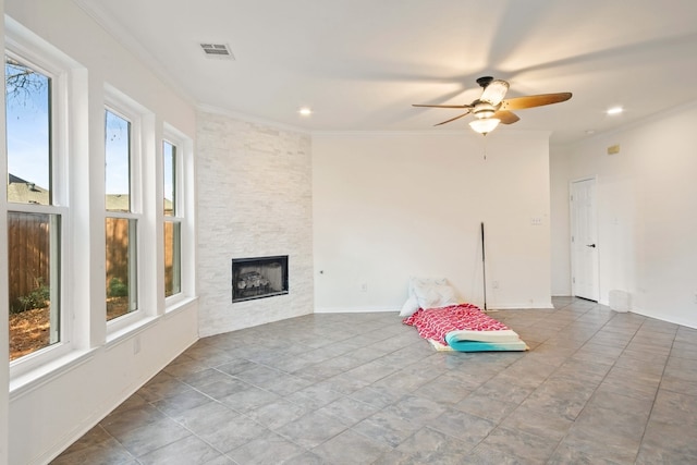 unfurnished living room with ceiling fan, ornamental molding, a fireplace, and a wealth of natural light