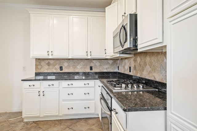 kitchen featuring white cabinets, dark stone countertops, appliances with stainless steel finishes, and tasteful backsplash