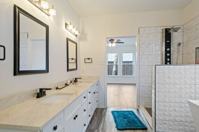 bathroom with tiled shower, ceiling fan, vanity, and hardwood / wood-style flooring