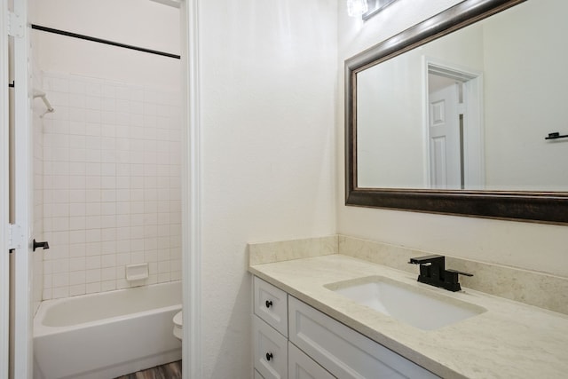 full bathroom with tiled shower / bath, vanity, and toilet