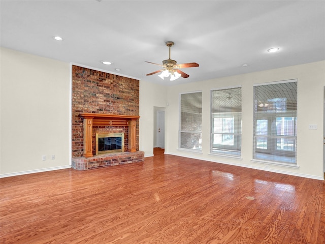 unfurnished living room with ceiling fan, wood-type flooring, and a brick fireplace