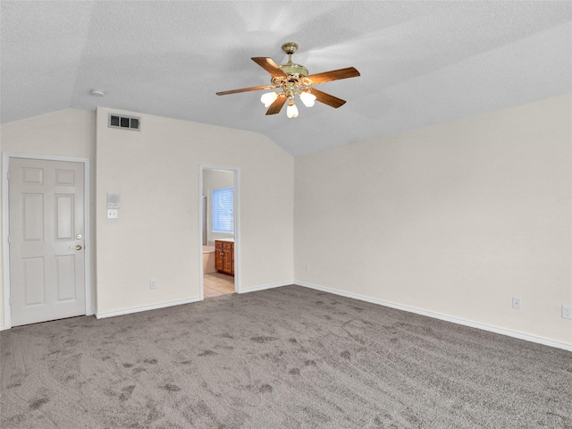 carpeted empty room featuring a textured ceiling, vaulted ceiling, and ceiling fan