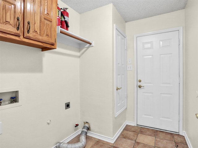 clothes washing area with hookup for a gas dryer, cabinets, a textured ceiling, and hookup for an electric dryer