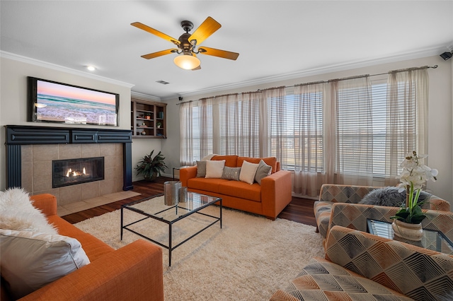 living room featuring hardwood / wood-style flooring, crown molding, ceiling fan, and a fireplace